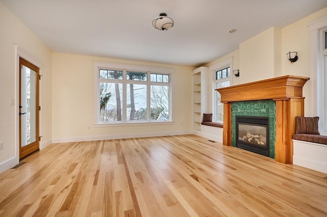 unfurnished living room featuring a tiled fireplace and light wood-type flooring