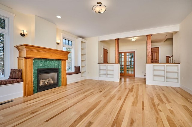 unfurnished living room featuring light hardwood / wood-style flooring, a fireplace, and a healthy amount of sunlight