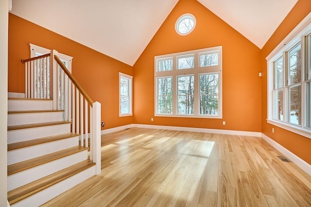 unfurnished living room with high vaulted ceiling and light hardwood / wood-style floors