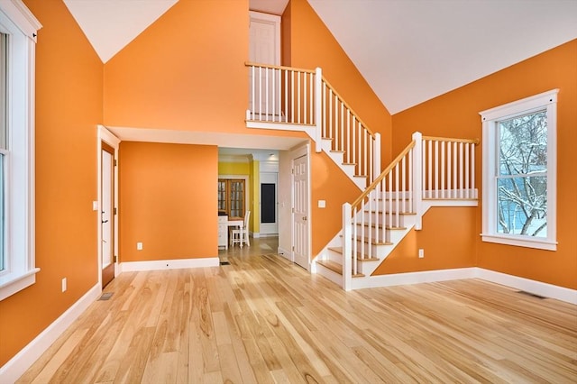 entryway with high vaulted ceiling and light wood-type flooring