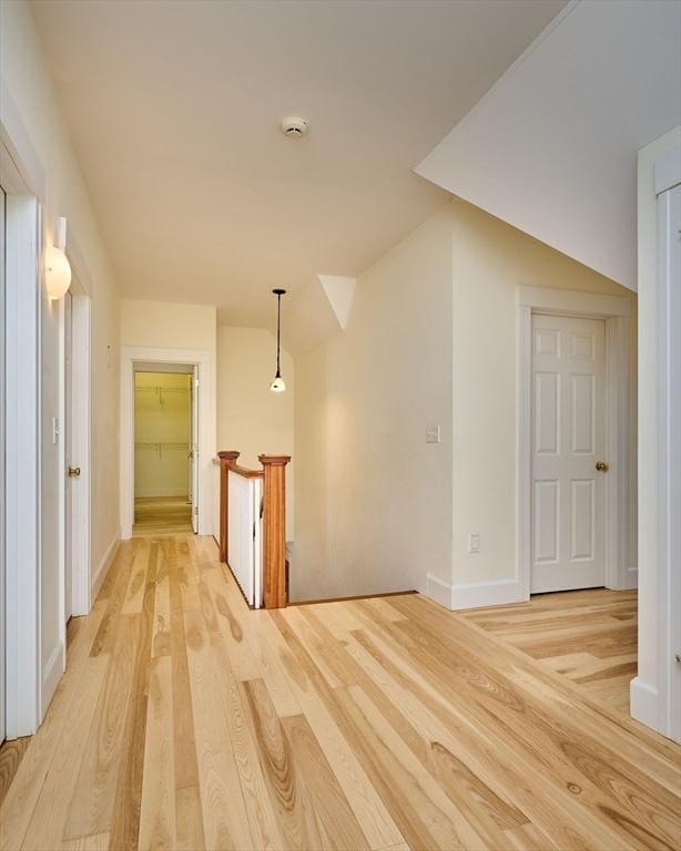 corridor with vaulted ceiling and light hardwood / wood-style floors