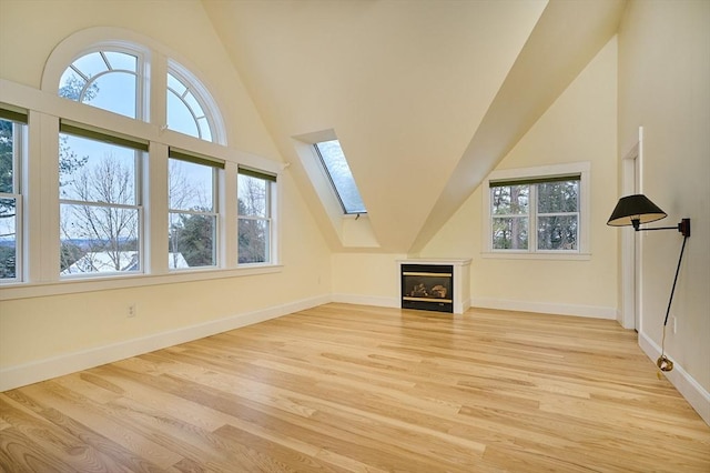 bonus room featuring plenty of natural light, lofted ceiling with skylight, and light wood-type flooring