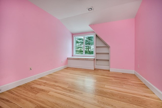 bonus room with vaulted ceiling and light wood-type flooring