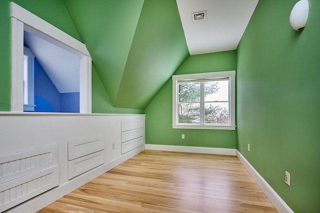 additional living space featuring vaulted ceiling and light wood-type flooring