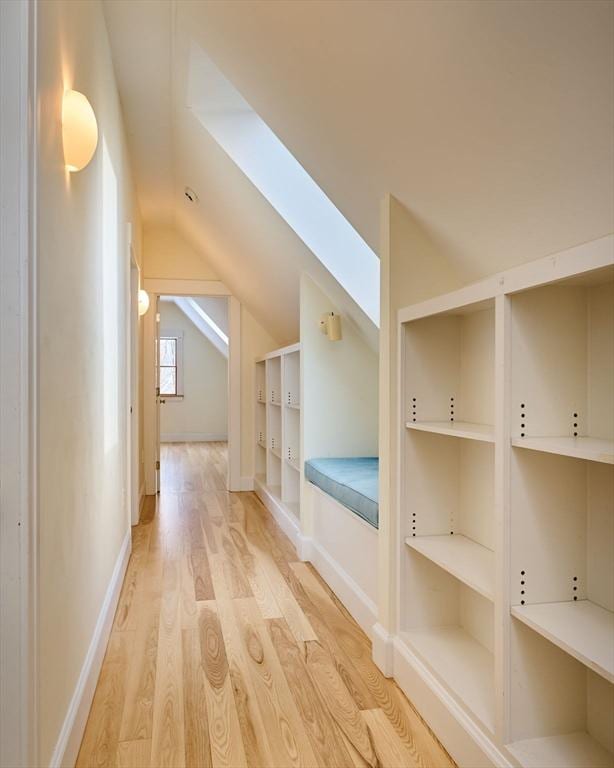 interior space featuring built in features, vaulted ceiling, and light hardwood / wood-style flooring