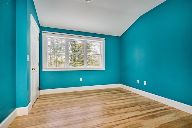 unfurnished room featuring lofted ceiling and light hardwood / wood-style floors