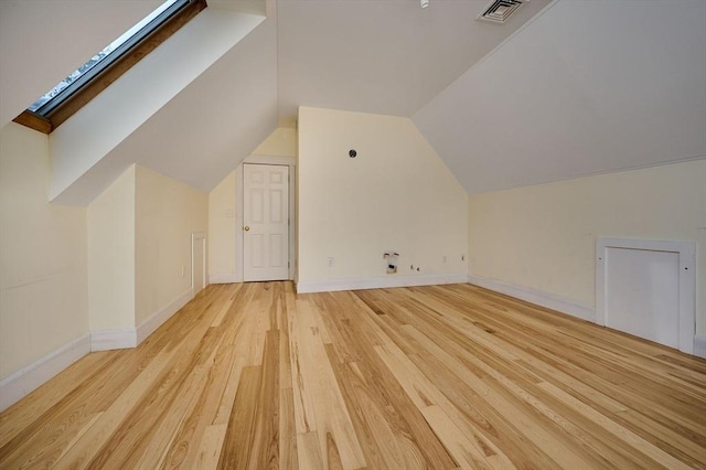 bonus room featuring vaulted ceiling with skylight and light wood-type flooring