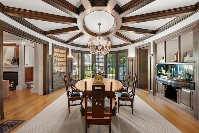 dining room with light wood-type flooring, beam ceiling, a notable chandelier, ornamental molding, and built in shelves