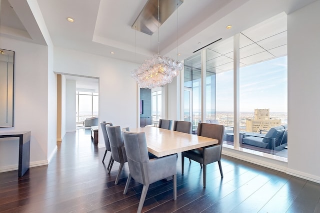 dining room with a tray ceiling, an inviting chandelier, and dark hardwood / wood-style flooring