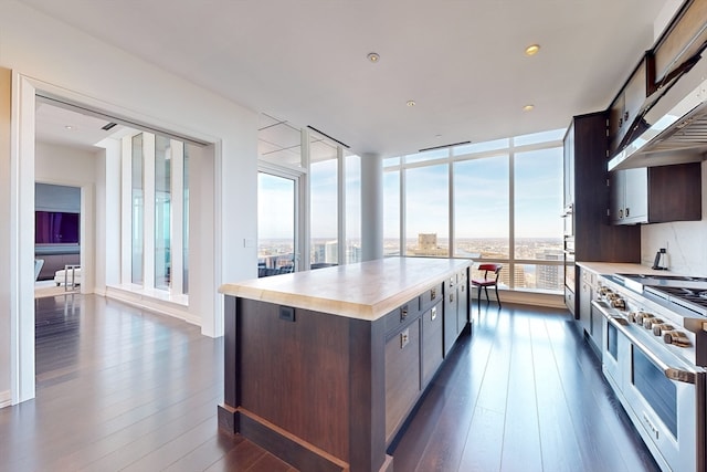 kitchen featuring a center island, range with two ovens, dark brown cabinetry, and dark hardwood / wood-style flooring