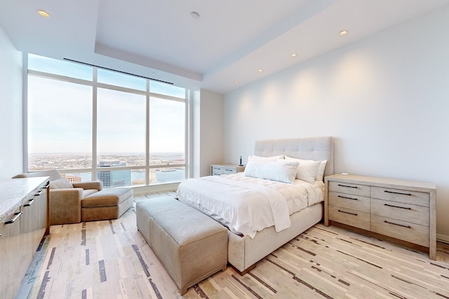 bedroom featuring expansive windows, light wood-type flooring, and a water view