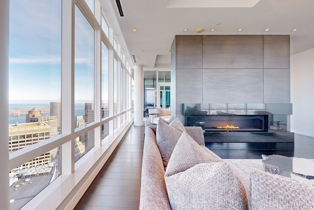 interior space featuring a wall of windows, a water view, dark hardwood / wood-style floors, and a fireplace