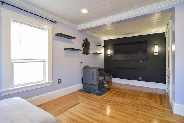 living area with ornamental molding, wood finished floors, a wood stove, and baseboards