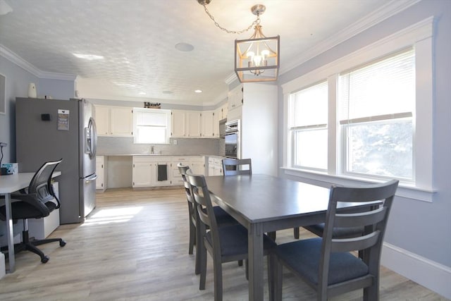 dining space featuring baseboards, an inviting chandelier, light wood-style flooring, and crown molding