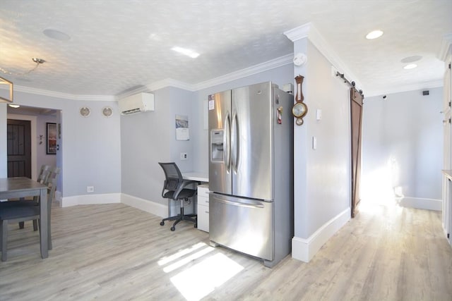 kitchen with a wall mounted air conditioner, stainless steel fridge, light wood-style flooring, and a barn door