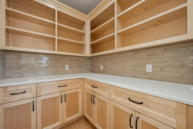 kitchen with light brown cabinetry and tasteful backsplash