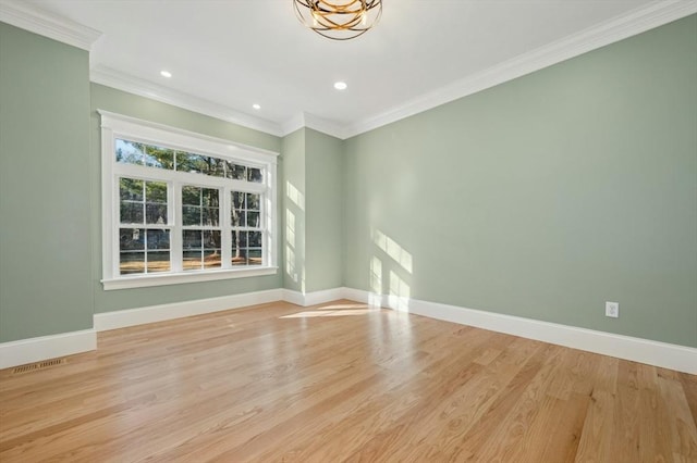 spare room with light wood-type flooring, crown molding, and a chandelier