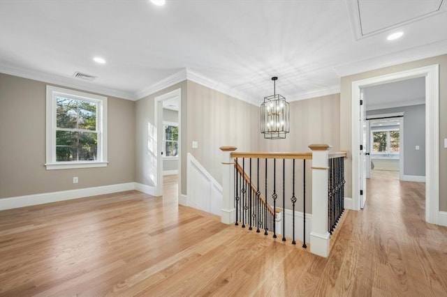 corridor with crown molding, light hardwood / wood-style flooring, and a notable chandelier