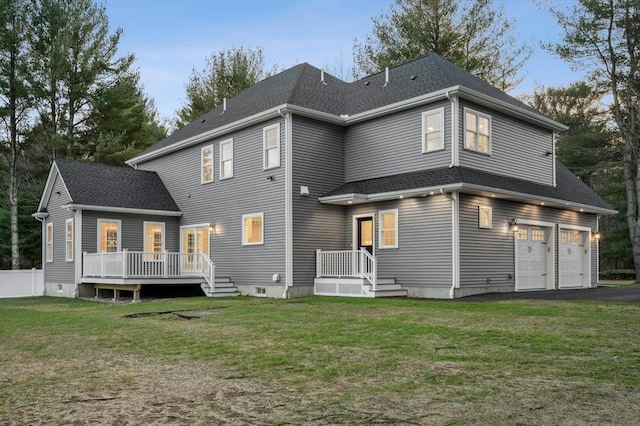 back of property featuring a garage, a deck, and a lawn