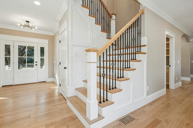 entrance foyer with crown molding, light hardwood / wood-style flooring, and an inviting chandelier