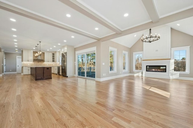 unfurnished living room with lofted ceiling with beams, light hardwood / wood-style flooring, and crown molding