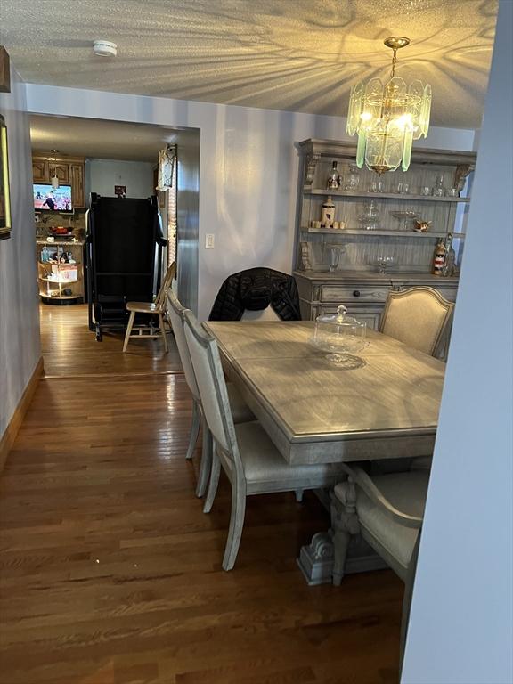 dining room with a chandelier, a textured ceiling, and dark hardwood / wood-style flooring