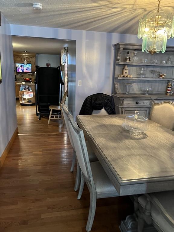 dining room with dark wood-type flooring and an inviting chandelier