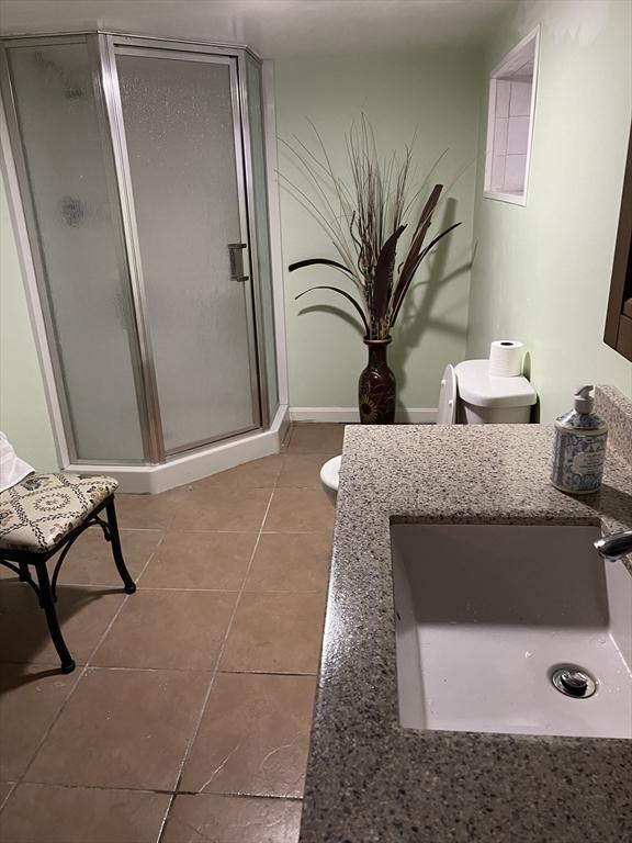 bathroom featuring toilet, tile patterned flooring, vanity, and walk in shower