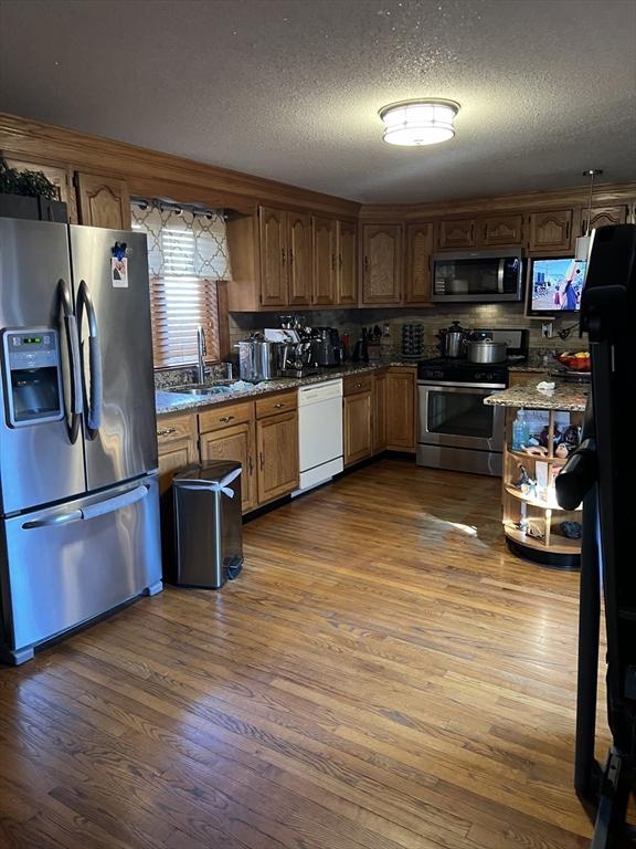 kitchen featuring appliances with stainless steel finishes, stone countertops, dark hardwood / wood-style floors, and sink