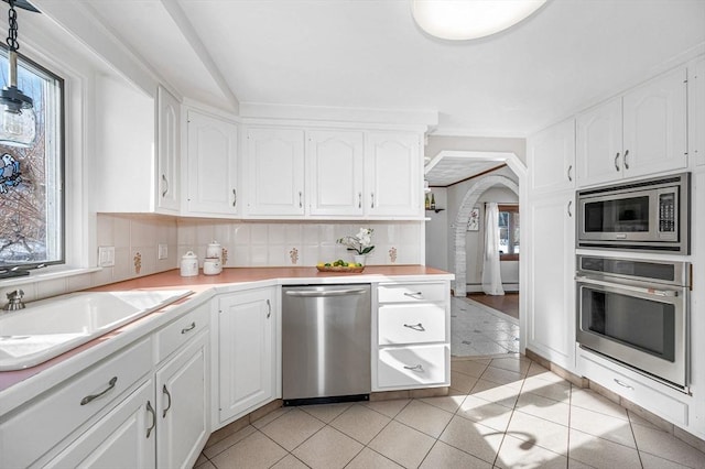 kitchen with backsplash, plenty of natural light, stainless steel appliances, and white cabinets