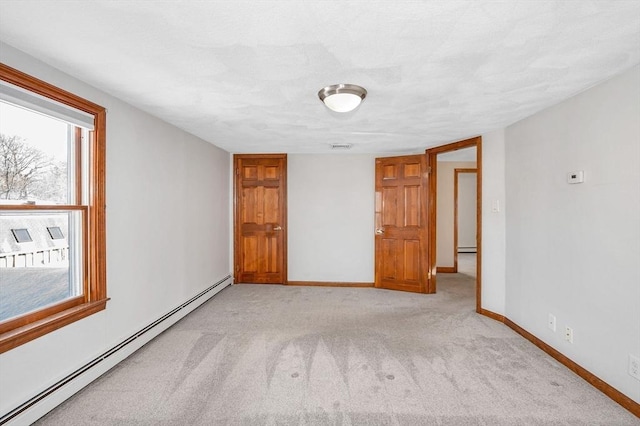 spare room with light carpet and a baseboard radiator