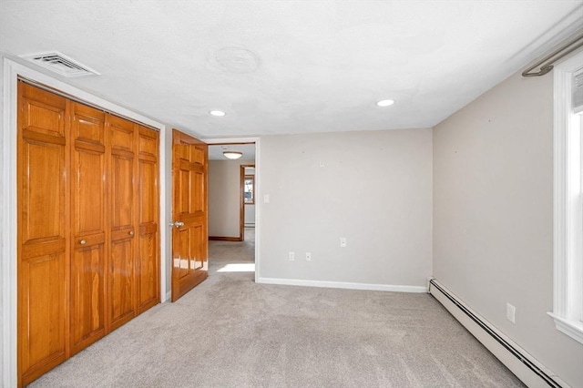 unfurnished bedroom featuring light carpet, baseboard heating, and a closet