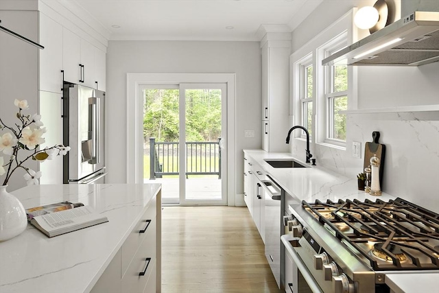 54 Stone Rd, Sudbury, MA 01776 - kitchen featuring a sink, stainless steel appliances, wall chimney range hood, light wood-style floors, and white cabinets