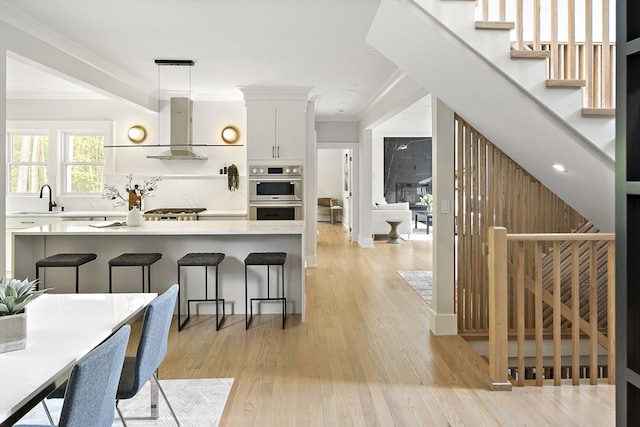54 Stone Rd, Sudbury, MA 01776 - kitchen featuring double oven, wall chimney range hood, a sink, a kitchen breakfast bar, and crown molding