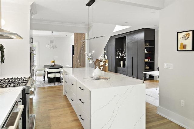 54 Stone Rd, Sudbury, MA 01776 - kitchen featuring light wood finished floors, wall chimney range hood, ornamental molding, white cabinetry, and light stone counters