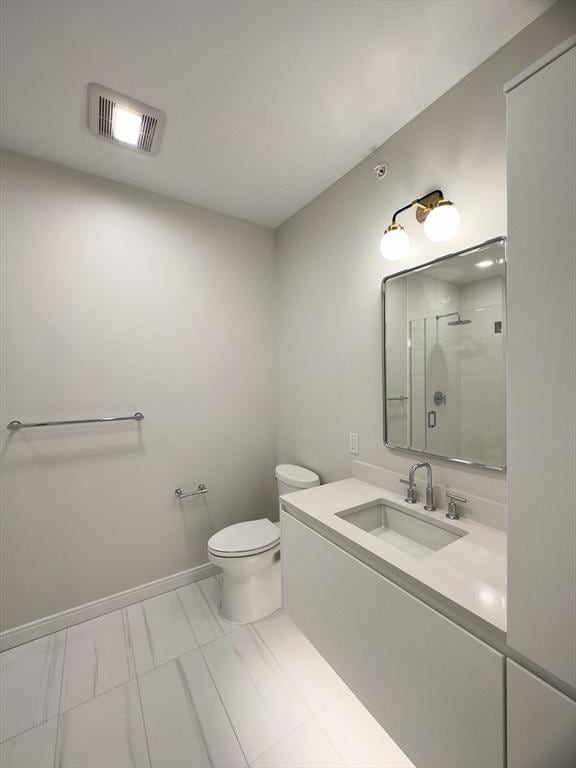 bathroom featuring a shower with door, vanity, and toilet