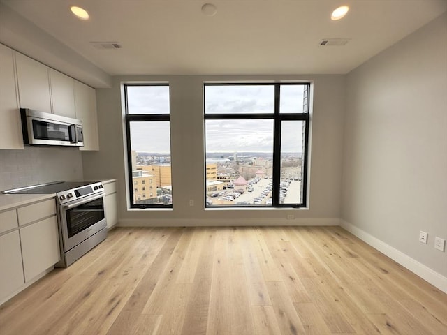 kitchen featuring white cabinets, decorative backsplash, stainless steel appliances, and light hardwood / wood-style floors