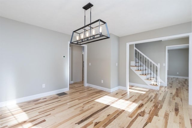 261/2 Cherry St, Spencer, MA 01562 - unfurnished dining area with light wood-style flooring, baseboards, stairway, and an inviting chandelier