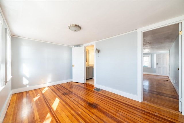 empty room with baseboards, visible vents, and hardwood / wood-style floors