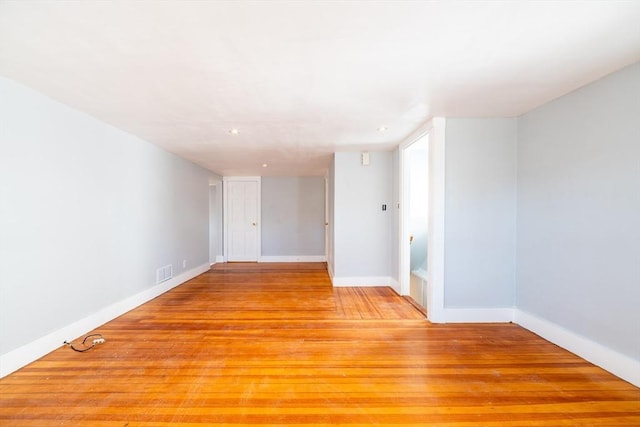 empty room with light wood-style floors, visible vents, and baseboards