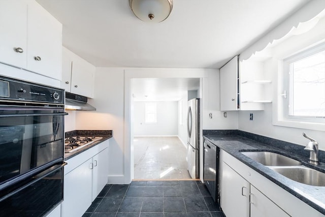 kitchen featuring under cabinet range hood, dark tile patterned flooring, a sink, white cabinets, and appliances with stainless steel finishes