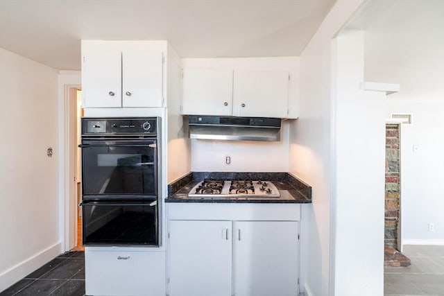 kitchen featuring dobule oven black, stainless steel gas stovetop, white cabinetry, dark tile patterned flooring, and under cabinet range hood