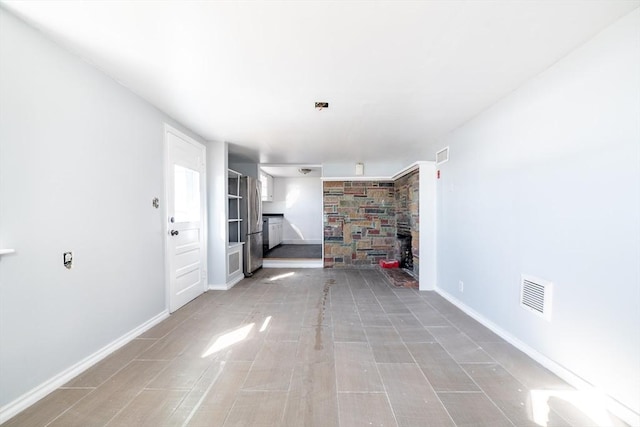 unfurnished living room with visible vents and baseboards