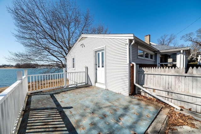 exterior space featuring a water view, fence, and a chimney