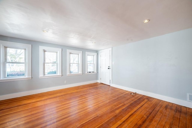 spare room featuring visible vents, hardwood / wood-style floors, and baseboards