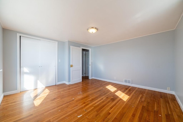 unfurnished bedroom featuring a closet, light wood-type flooring, visible vents, and baseboards