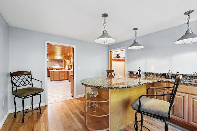 1 Sheffield Cir, Andover, MA 01810 - kitchen with open shelves, dark stone counters, a breakfast bar area, light wood finished floors, and decorative light fixtures
