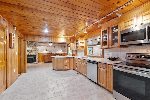 1 Sheffield Cir, Andover, MA 01810 - kitchen featuring stainless steel appliances, track lighting, wood walls, light countertops, and a stone fireplace