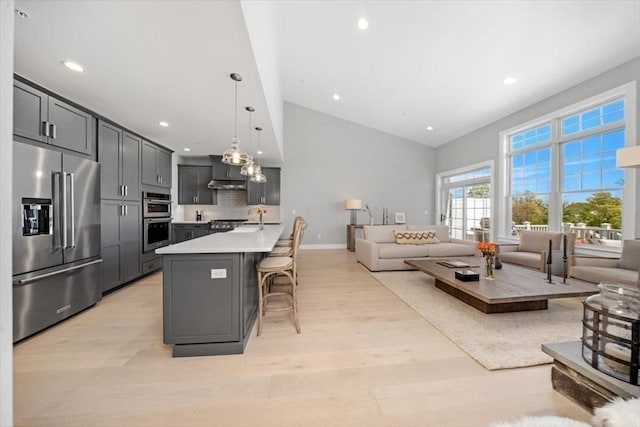 21 Brand Blvd Unit 21, Scituate, MA 02066 - kitchen featuring stainless steel appliances, open floor plan, a breakfast bar area, light wood finished floors, and high vaulted ceiling