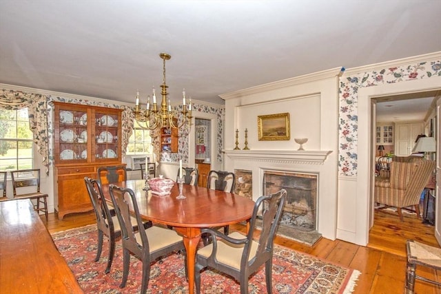 dining space with ornamental molding, wallpapered walls, light wood-style flooring, and a chandelier
